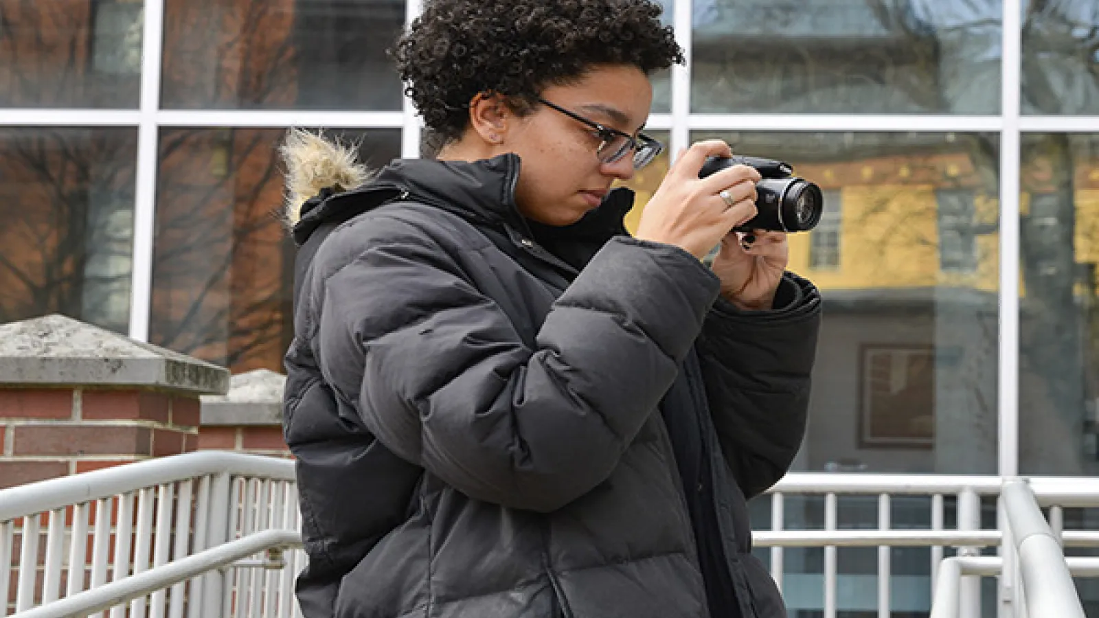 Student adjusting digital camera to shoot