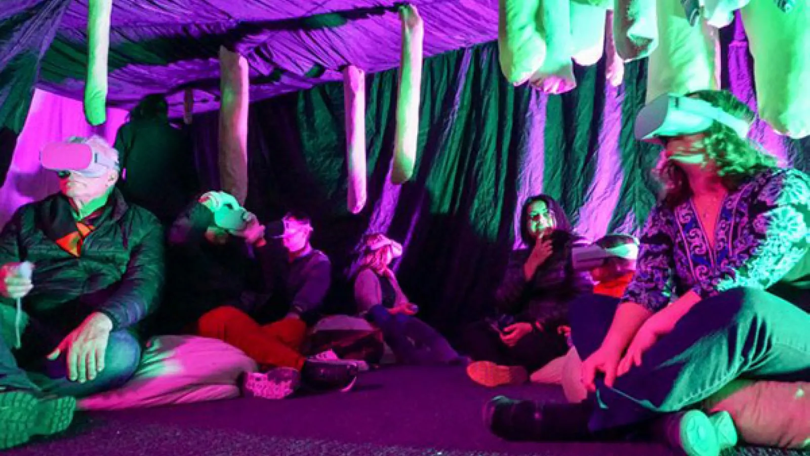 green tubes hanging from the ceiling people sitting underneath wearing virtual reality headsets