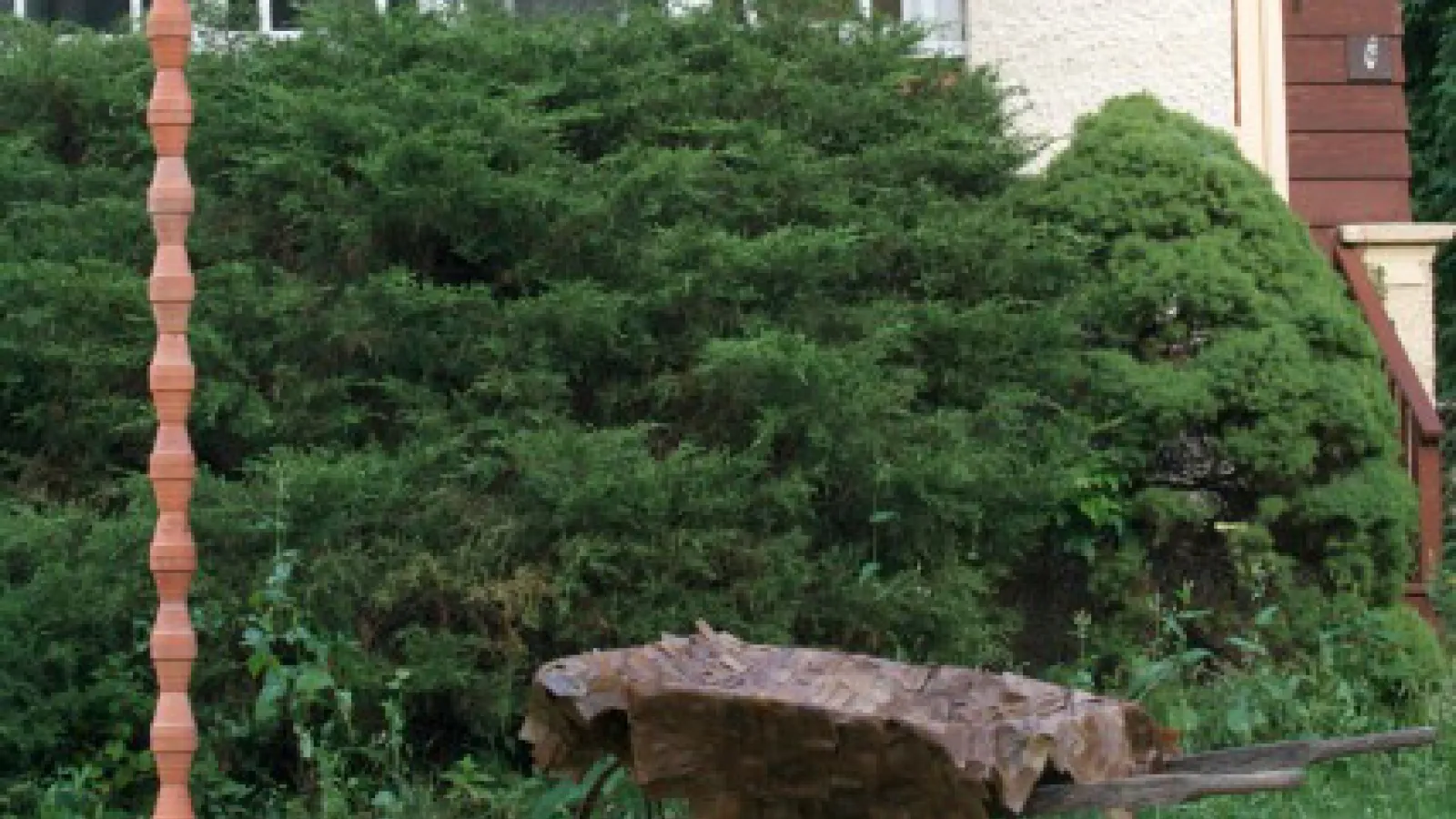 a metal sculpture in front of green bushes