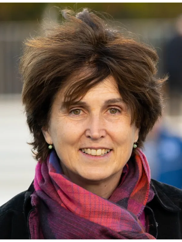 a smiling person with brown hair wearing a fuchsia and purple scarf