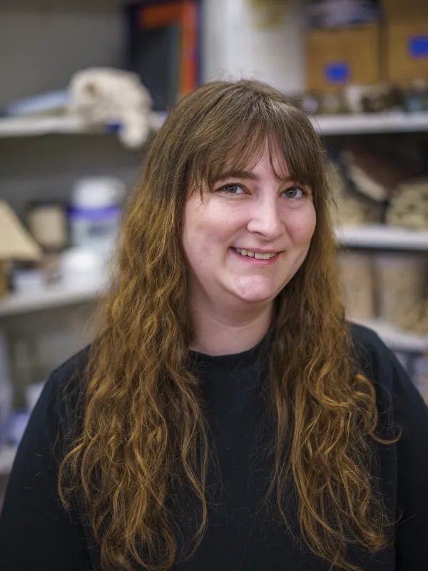 a person with long hair smiles looking into the camera
